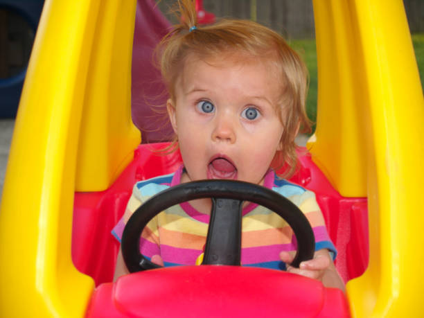 Girl in Toy Car A girl in a toy car surprised and happy or a reaction to hitting something while playing kid toy car stock pictures, royalty-free photos & images