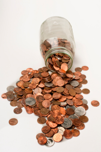 A glass jar full of coins  on a white background with copy space