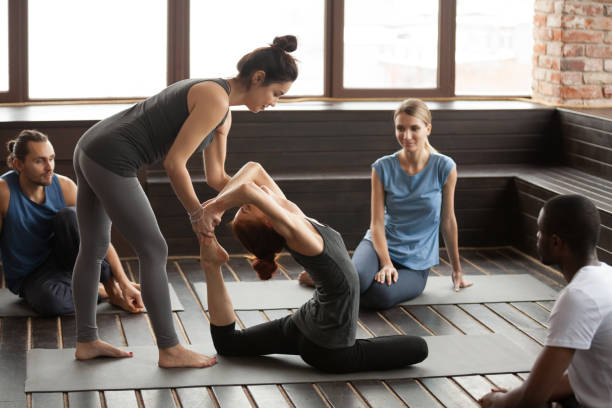 istock Female yoga instructor helping woman doing exercise at group training 922482568