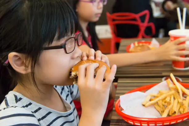 Photo of Asian kid eating a hamburger and french fries