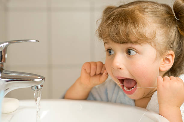 かわいい女の子のフロスの歯のクリーニング - child smiling human teeth dental hygiene ストックフォトと画像