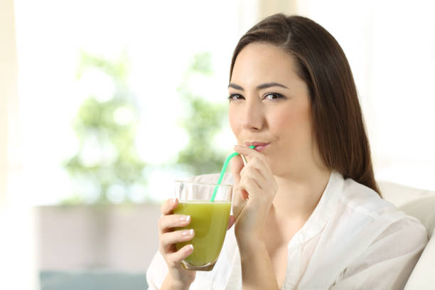 istock Girl drinking a vegetable green juice looking at you 922496546