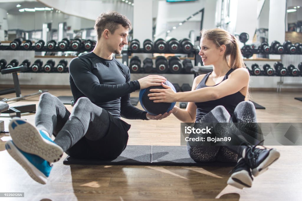 Sporty fitness couple doing abdominal exercises with medicine ball in the gym. Exercising Stock Photo