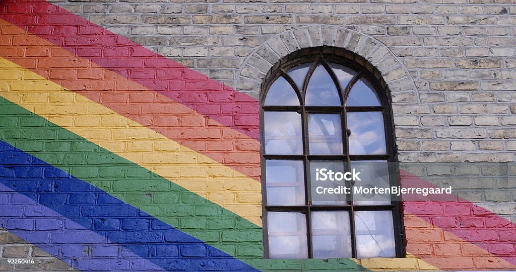 Colurfull Window Framed Rainbow painted on wall with old style windowframe. Blue Stock Photo