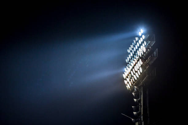 Light tower lit at a stadium during nightime. stock photo