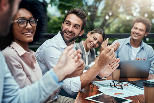 Shot of a group of colleagues applauding during a meeting at a cafe