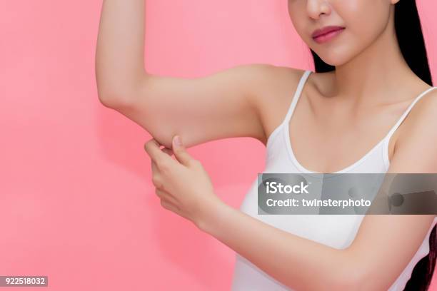 Young Attractive Asian Woman Pinching Excess Fat And Cellulite In Her Upper Arms As She Lacks Exercise And Healthy Lifestyle Stock Photo - Download Image Now