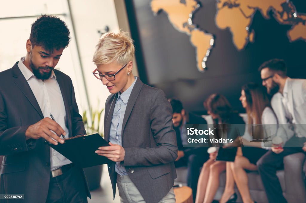 Business people working Businessman and businesswoman reviewing contract; business team working in the background Global Business Stock Photo