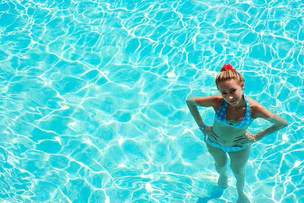 Photo of a beautiful young Hispanic woman wading in a swimming pool on a sunny summer day