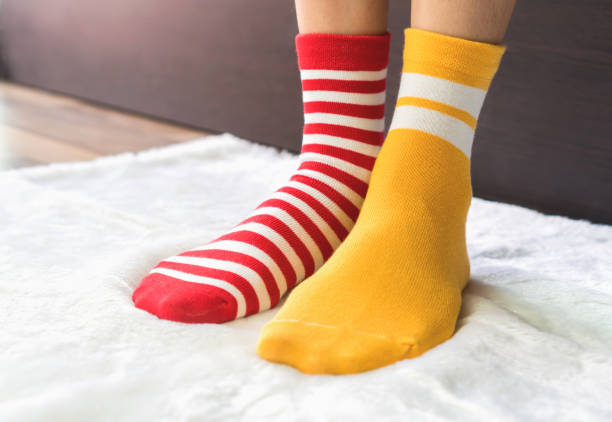 pieds en chaussettes de deux couleurs alternées, rouge et jaune côté stand à étage de tissu blanc. - plaid textile red cotton photos et images de collection