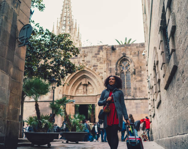 Mixed race woman have just arrived in Barcelona Smiling woman admiring the architecture while pulling a suitcase in Barcelona african american architecture stock pictures, royalty-free photos & images