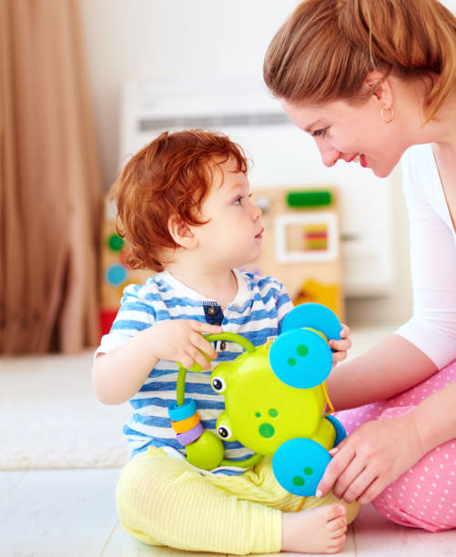vrolijke jonge vrouw, moeder spelen van spelletjes met kinderen bij kinderdagverblijf room - pregnant count stockfoto's en -beelden