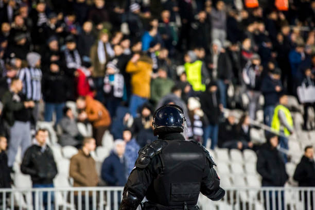 the police at the stadium event secure a safe match against the hooligans - riot imagens e fotografias de stock