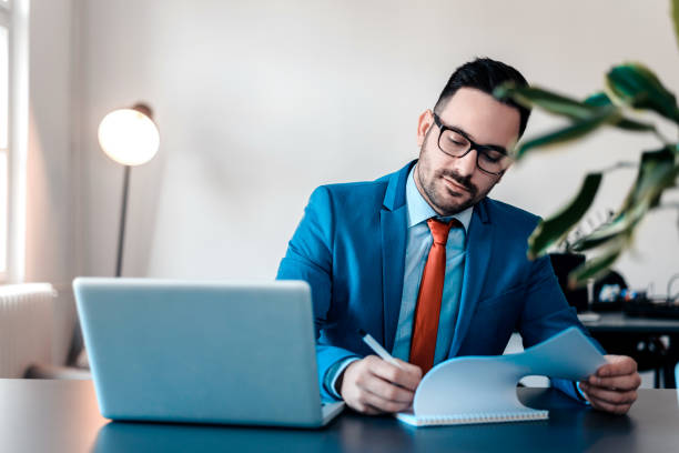 istock A businessman writing down something while sitting at the desk in his office. 922530282