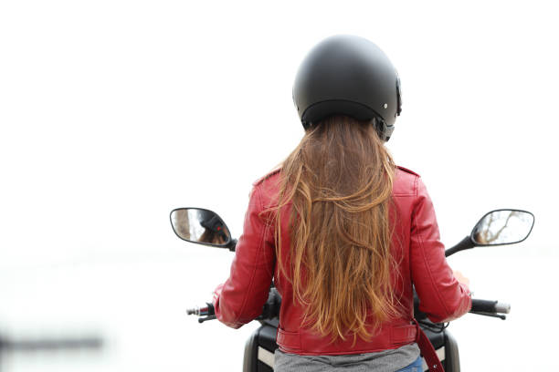Back view of a motorbiker sitting on a motorcycle on white background