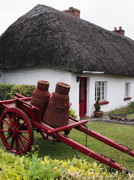 istock White thatched cottage with a red milk cart 92253171
