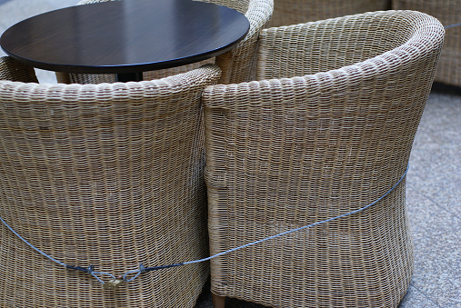 Wooden chairs and a table of a street cafe closed with a metal cable and a padlock