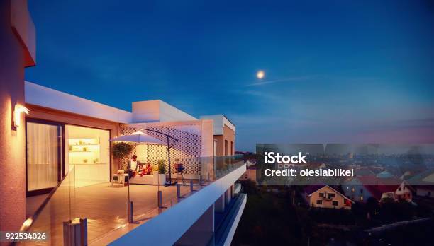 Family Relaxing On Roof Top Patio With Evening City View Stock Photo - Download Image Now