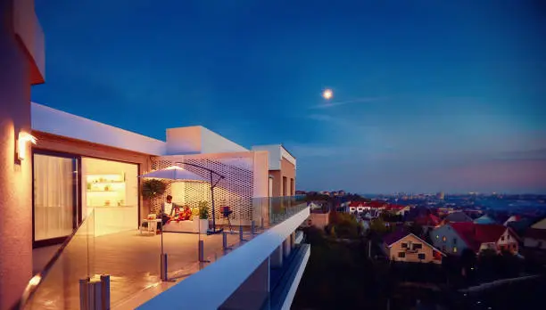 Photo of family relaxing on roof top patio with evening city view