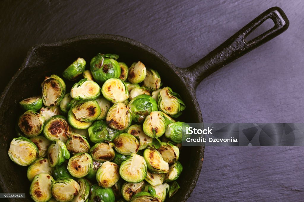 Vegetarian cuisine. Brussels Sprouts roasted with olive oil. Copyspace Vegetarian cuisine. Homemade Brussels Sprouts roasted with olive oil on black slate background. Copyspace, top view, flatlay. Brussels Sprout Stock Photo