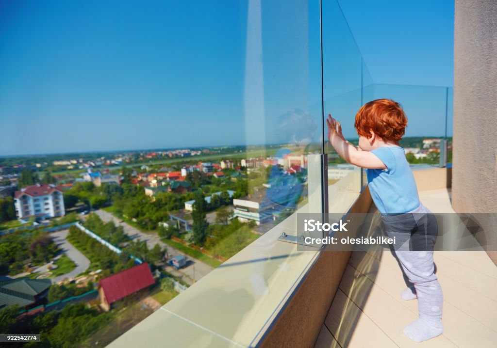 infant baby boy enjoying the city view from the rooftop patio at multi storey building Glass - Material Stock Photo