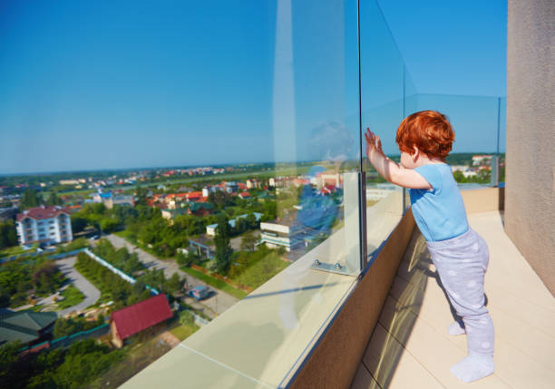 infant baby boy enjoying the city view from the rooftop patio at multi storey building infant baby boy enjoying the city view from the rooftop patio at multi storey building balustrade stock pictures, royalty-free photos & images
