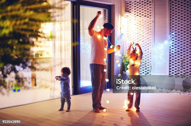 Famiglia Felice Padre Con Figli Decorare Area Patio Open Space Con Ghirlande Di Natale - Fotografie stock e altre immagini di Natale