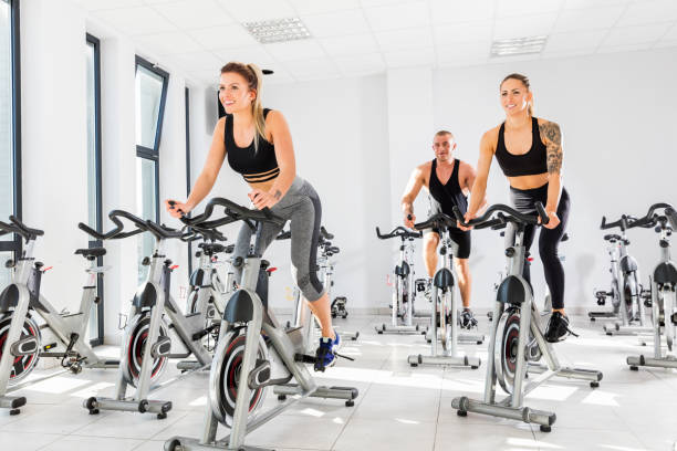 Group of fit people training at exercising class. Group of fit people training at exercising class. Cardio workout. Indoor cycling. spin bike stock pictures, royalty-free photos & images