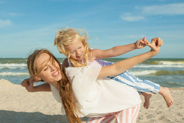 Madre e figlia si divertono a giocare sulla spiaggia - foto stock