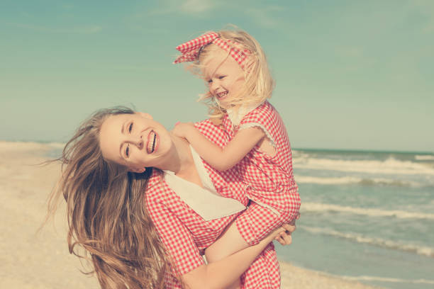 Madre e figlia si divertono a giocare sulla spiaggia - foto stock