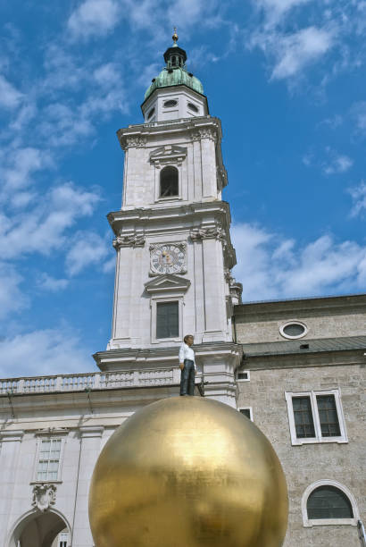 Sculpture of a man on a golden sphere on the Kapitelplatz next to the Salzburger Dom in Salzburg, Austria