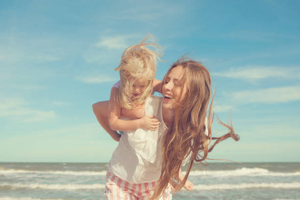 istock Mother and daughter having fun playing on the beach 922558944