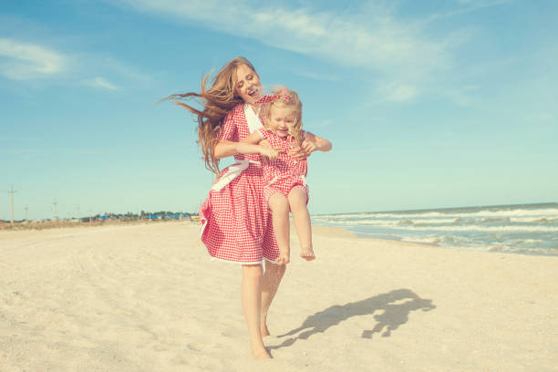 istock Mother and daughter having fun playing on the beach 922559008