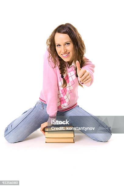 Estudiante Sentado En El Montón De Libros Y Mostrando Pulgar Hacia Arriba Foto de stock y más banco de imágenes de Adolescente