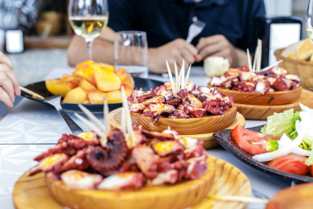 les gens manger pulpo a la gallega avec pommes de terre. plats de poulpe galicien. plats célèbres de galice, espagne. - wine food fish seafood photos et images de collection