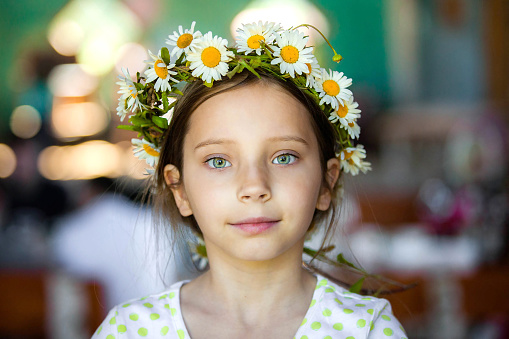 Young cute white girl wearing a chamomile wreath on head close up