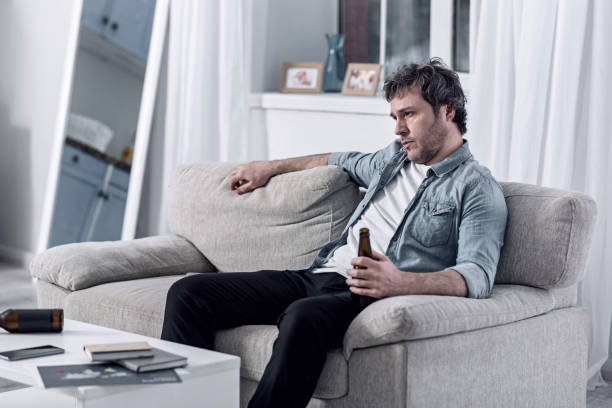 istock Bored alcohol addicted man sitting alone and drinking beer 922578596