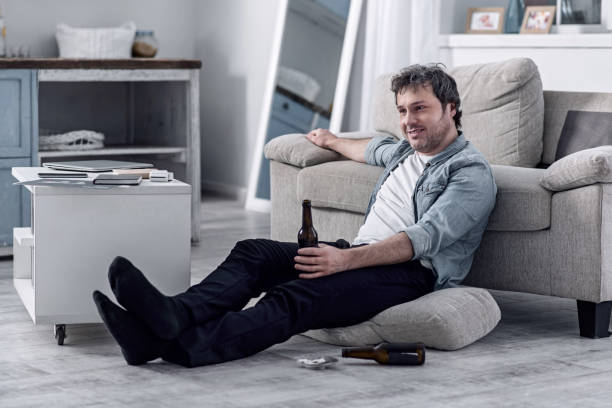 istock Smiling untidy man drinking alcohol and watching TV at home 922579008