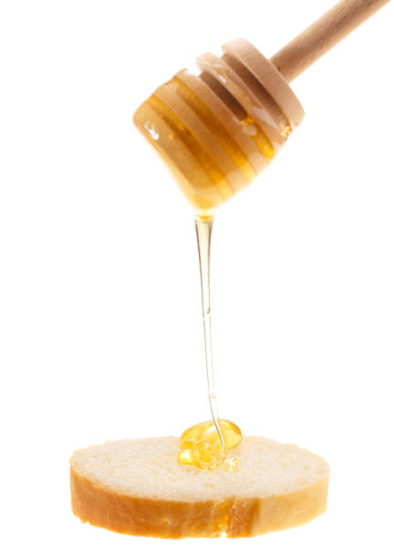 istock Honey is applied to the surface of bread. Isolated on a white background. 922579114