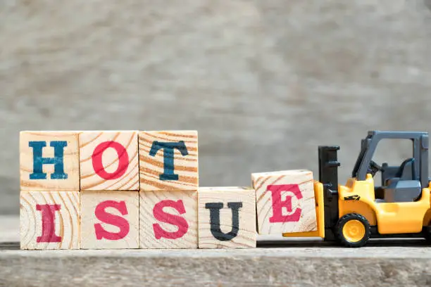 Photo of Toy forklift hold letter block e to complete word hot issue on wood background