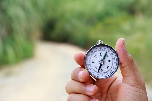 Male hand holding compass outdoors