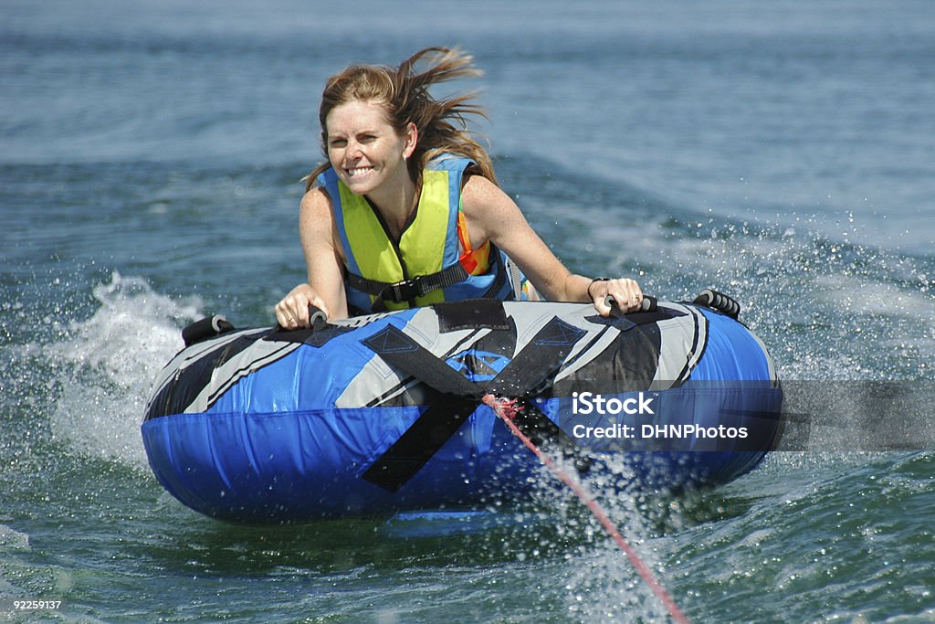 Giovane donna adulta il tubo interno dietro in motoscafo - Foto stock royalty-free di Andare in barca a vela