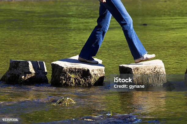 A Person Crossing Three Stepping Stones On A River Stock Photo - Download Image Now - Walking, Stone - Object, Staircase