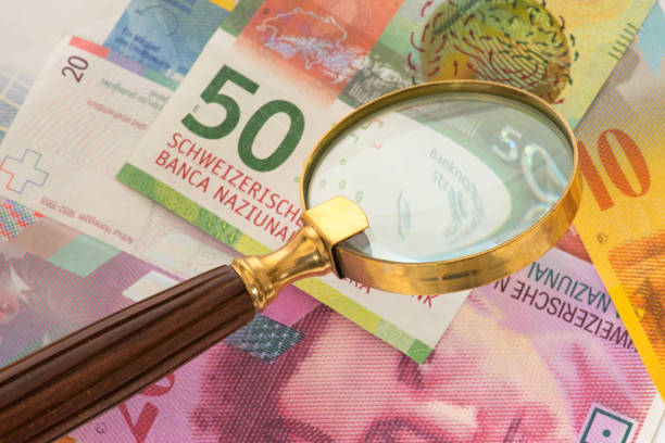 istock Swiss franc banknotes and a magnifying glass 922599804