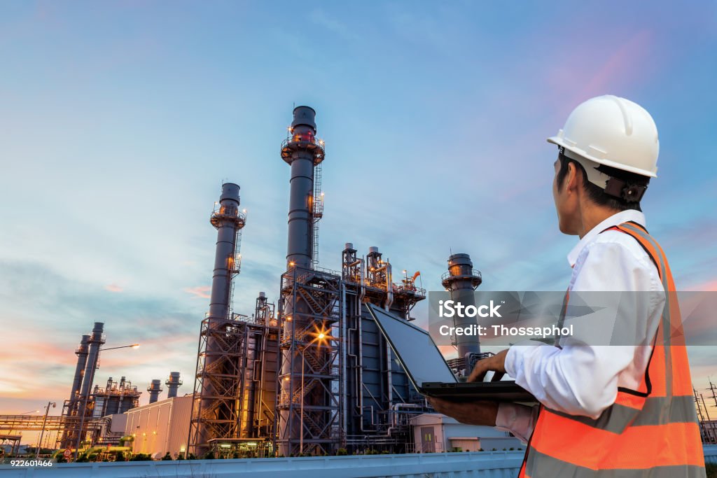 Engineering is use notebook check and standing in front of oil refinery building structure in heavy petrochemical industry Motor Oil Stock Photo