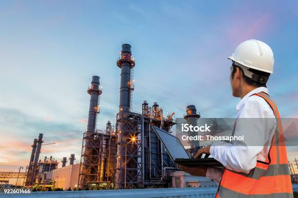 Engineering Is Use Notebook Check And Standing In Front Of Oil Refinery Building Structure In Heavy Petrochemical Industry Stock Photo - Download Image Now