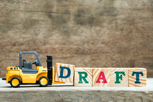 istock Yellow toy forklift hold letter block D to complete word draft on wood background 922608038