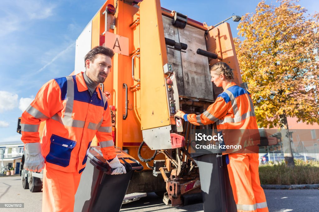 Waste collector gripping handle of garbage truck Waste collector gripping handle of garbage truck riding on the platform Garbage Truck Stock Photo