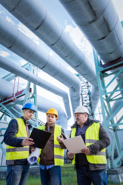 Engineers discussing maintenance of a petrochemical plant Engineers discussing maintenance of a petrochemical plant. Technical inspection. Oil and gas industry. motor oil photos stock pictures, royalty-free photos & images