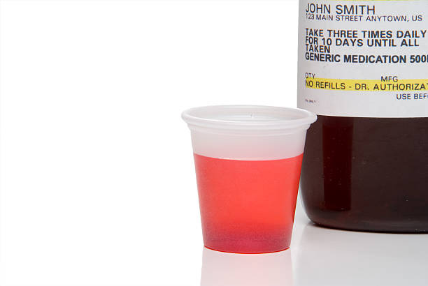 A bottle of prescription medicine and some red liquid stock photo